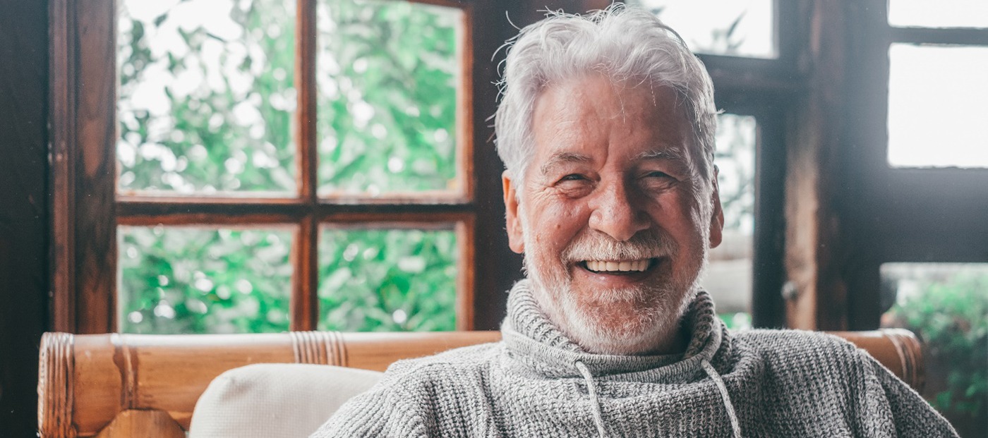 An older man looking at a camera and smiling