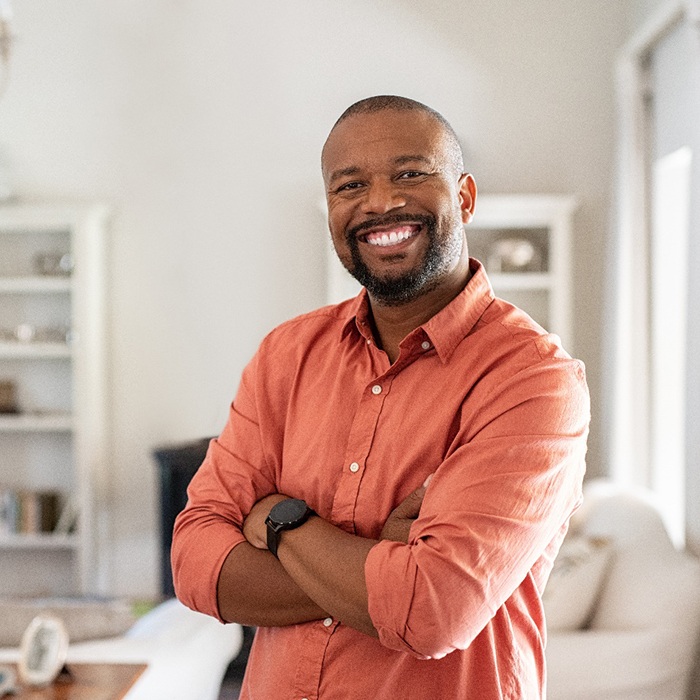 Man in button-up shirt smiling with arms folded