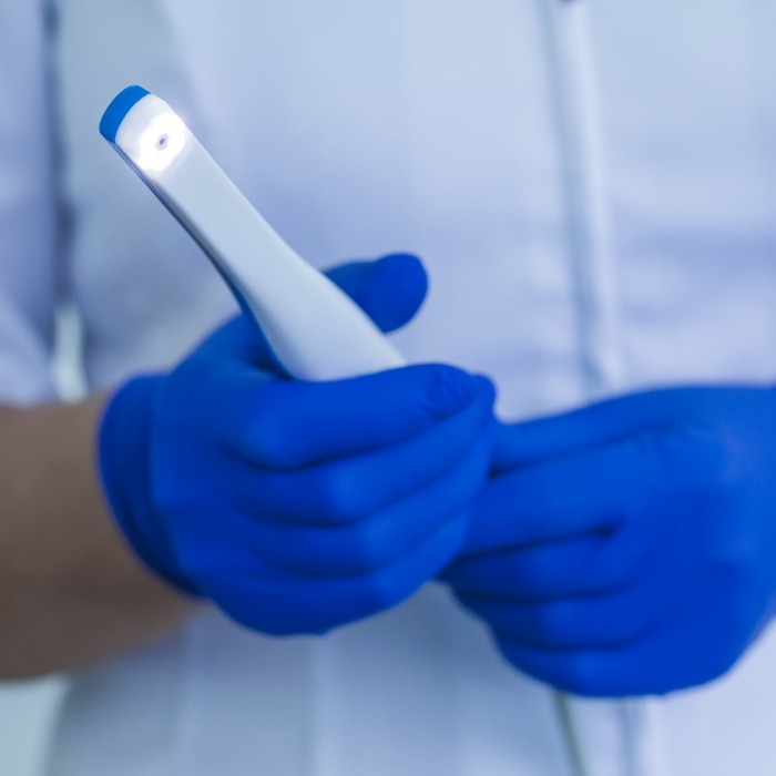 Gloved hands holding a thin white intraoral camera