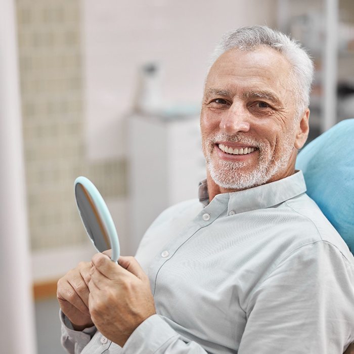 man smiling while sitting in dental chair 