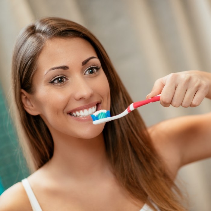 Woman smiling while brushing her teeth