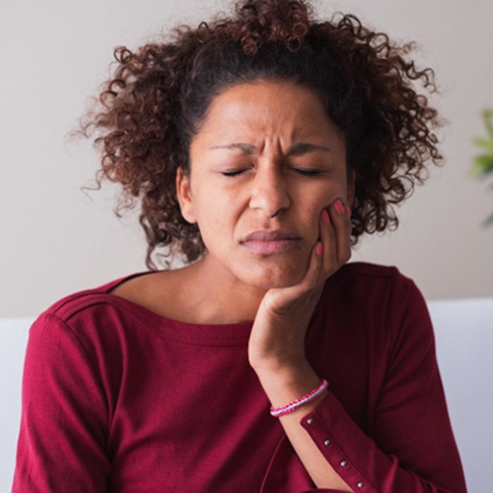 Woman with toothache sitting on couch at home