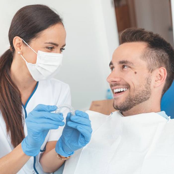 Patient and dentist looking at scans of teeth in computer screen