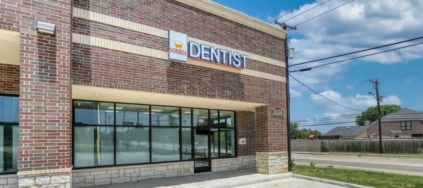 Woman in orange blouse smiling with dental implants in Arlington