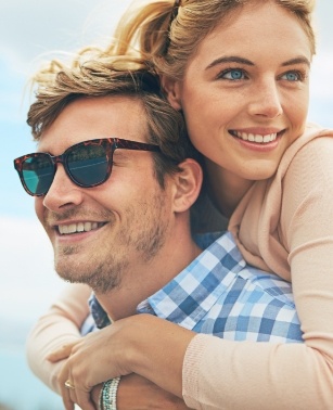 Young man giving young woman a piggyback ride outdoors